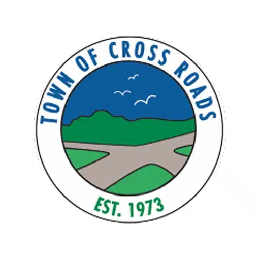 The seal of the Town of Cross Roads features intersecting roads, green hills, birds, and the text "Town of Cross Roads Est. 1973" in a circular border.